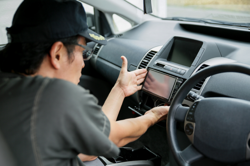 自動車整備士が車内のカーナビ・計器類を設置・調整している写真